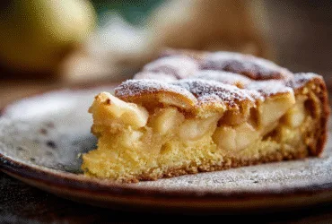 Part de gâteau aux pommes moelleux avec morceaux apparents sur assiette rustique.
