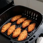 Aiguillettes de poulet airfryer dorées disposées en une seule couche dans le panier
