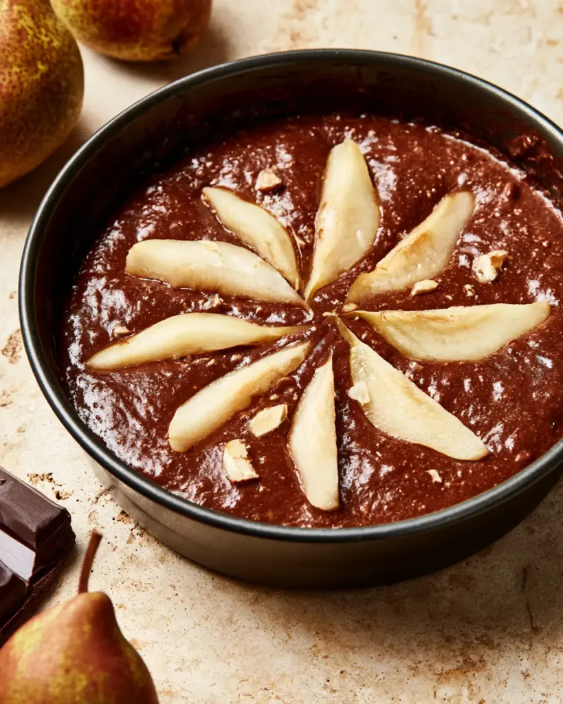 Poires en quartiers enfoncées dans la pâte au chocolat Quartiers de poire disposés en rosace sur la pâte du gâteau poire chocolat amande avant cuisson